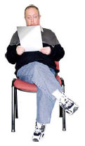 Photo of a man with learning disabilities sitting on a chair reading a pamphlet
