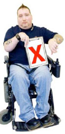 Man in a wheelchair holding a clipboard with a red cross on it